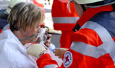 Foto: Ein DRK-Helfer versorgt eine Frau mit einer Sauerstoffmaske